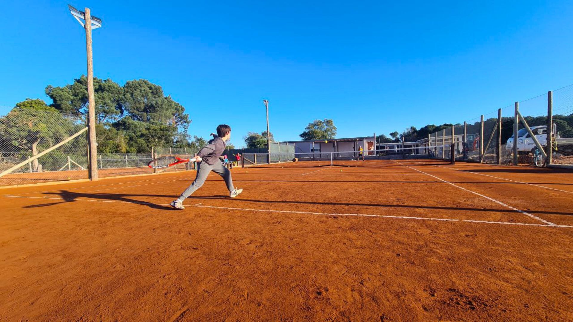 Jugador practicando tenis en una cancha del club